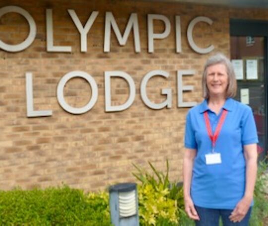 Woman in blue polo shirt standing outside Olympic Lodge