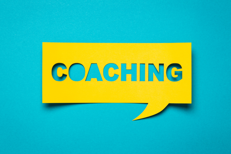 Yellow speech bubble on blue background with the word "coaching" cut out.