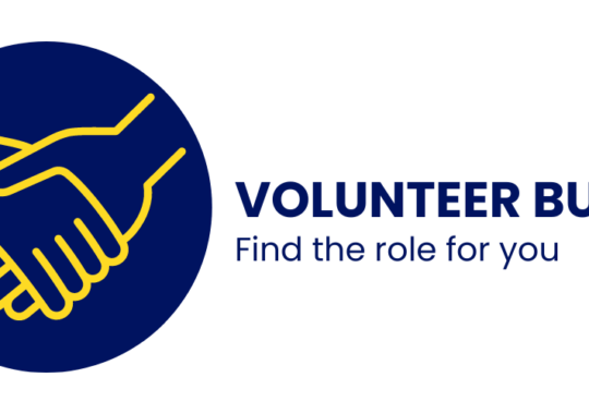 Blue round logo with two yellow hands shaking in the middle, with words Volunteer Bucks - find the role for you